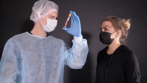 Muž v ochranném oděvu dává pilulku dívce s nápisem covid-19 na levém obočí. Doktor smaže virus z dívčího čela.. — Stock video