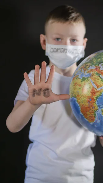 Il bambino allunga la mano in avanti Stop, NO. Ragazzo sta tenendo un globo, un modello del pianeta Terra. Il ragazzo sta attento al virus. Pandemia marzo 2020. Coronavirus. COVID-19 — Foto Stock