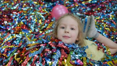Küçük kız renkli kağıt şeritlerin üzerinde yatıyor. Şirin bebek yüzü..