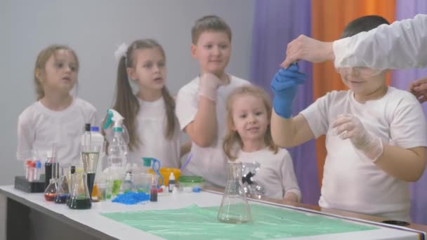Experimentos químicos para niños. Una mujer añade ingredientes a un frasco para experimentos químicos. Una columna de humo sale del vaso de precipitados. Emociones brillantes de niños y adultos, sorpresa, admiración — Vídeos de Stock