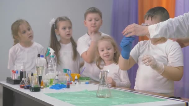 Experimentos químicos para niños. Una mujer añade ingredientes a un frasco para experimentos químicos. Una columna de humo sale del vaso de precipitados. Emociones brillantes de niños y adultos, sorpresa, admiración — Vídeos de Stock