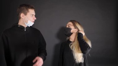 Tıbbi maskeli bir kızla bir adam. Bir adam bir kadına sarı bir balondan sıvı püskürtür. Dezenfektan solüsyonu sıkıyorum. İnsanların vahşi duyguları..