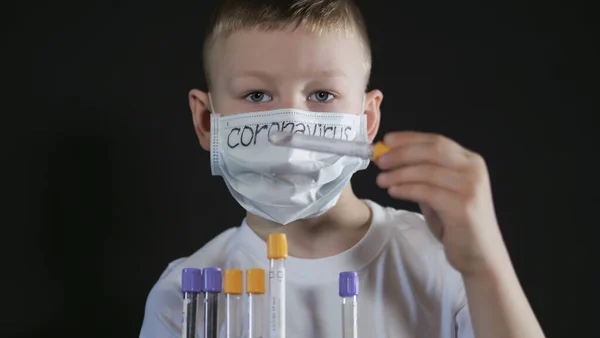 O rapaz tem uma mala de metal. Criança examina um tubo de teste médico com uma amostra para o vírus. O rapaz tem cuidado com o vírus. Pandemia Março 2020. Coronavírus. COVID-19 Imagens Royalty-Free
