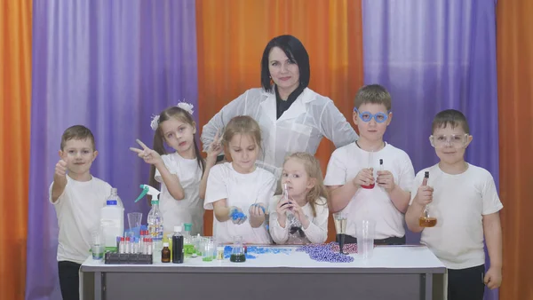 Child is holding flasks of colored liquid. Chemical experiments for children. Fun experiments for children. Children have fun and learn. Bright childrens emotions.