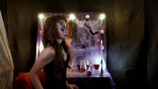Meisje met make-up voor Halloween zit voor een spiegel. De kunstenaar gooit een haarlok van haar gezicht. Een clown komt achter haar, glimlachend, en legt zijn handen op de nek van de meisjes. Bruiden — Stockvideo