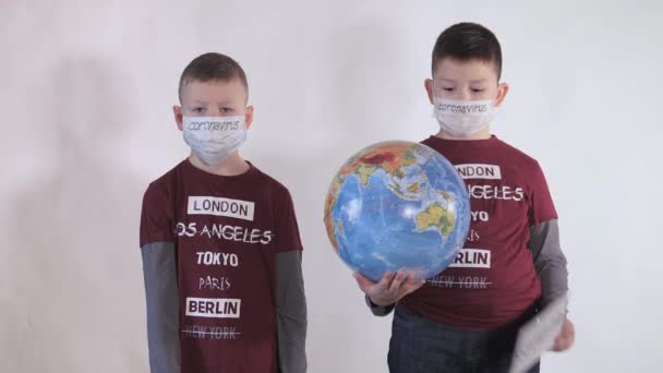 Baby reikt naar voren STOP, NO. Jongen heeft een wereldbol, een model van de planeet Aarde. Kind draagt een bord met de inscriptie: COVID-19. Jongen is voorzichtig met het virus. Pandemie maart 2020 — Stockvideo