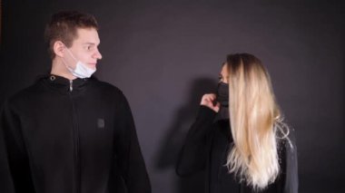 Tıbbi maskeli bir kızla bir adam. Bir adam bir kadına sarı bir balondan sıvı püskürtür. Dezenfektan solüsyonu sıkıyorum. İnsanların vahşi duyguları..