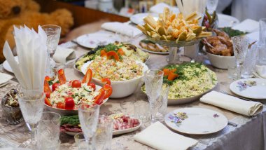 Masa ayarı. Atıştırmalıklı tabaklar, şenlikli ev yemeği masasının üzerine güzelce yerleştirilmiş. Yemek tabakları ve bardaklar masaya konur..