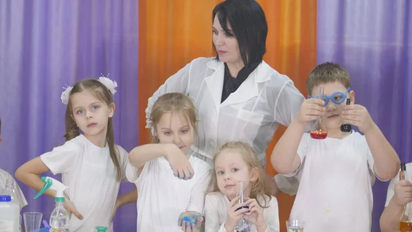 Ребенок держит фляжки с цветной жидкостью. Химические эксперименты для детей. Веселые эксперименты для детей. Дети веселятся и учатся. Яркие детские эмоции . — стоковое фото