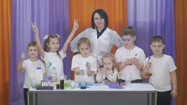 El niño sostiene frascos de líquido de color. Experimentos químicos para niños. Divertidos experimentos para niños. Los niños se divierten y aprenden. Niños brillantes emociones . —  Fotos de Stock