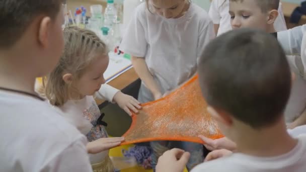 Esperimenti chimici per bambini. Le persone allungano la sostanza viscosa in direzioni diverse. Emozioni lucenti di bambini. La stanza è piena di fumo artificiale . — Video Stock