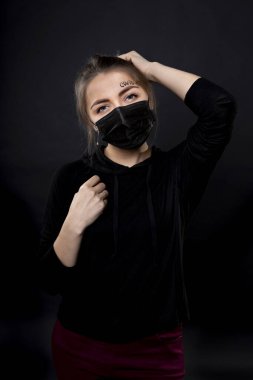 Woman in a black protective mask with the words covid-19 written on her forehead. clipart