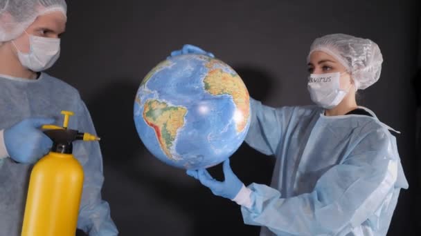 Decontamination of the planet Earth. Man in a protective suit and a medical mask. Guy is holding a yellow spray can.young woman in protective clothing. On the face of a protective medical mask. On the — Stock Video