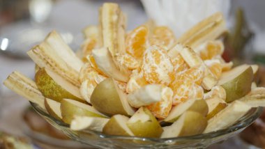 Masa ayarı. Bir kase meyve. Armut dilimleri, mandalina dilimleri ve yemek için istiflenmiş muz dilimleri..