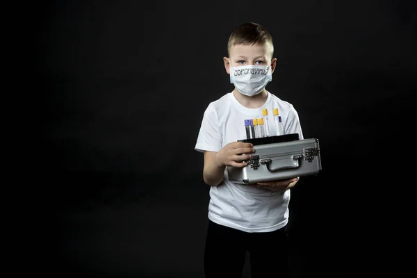 Il ragazzo ha in mano una valigia di metallo. Il bambino esamina una provetta medica con un campione per il virus. Il ragazzo sta attento al virus. Coronavirus . — Foto Stock
