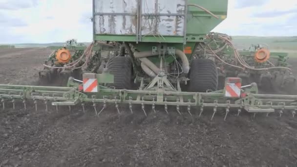 Zaaien in het veld. De zaaimachine verdeelt zaden en meststoffen over het omgeploegde land. Universele landbouwtrekker. — Stockvideo