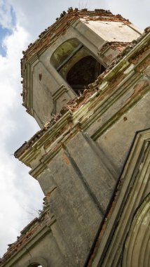 Tapınağın alçılı beyaz cephesi. Eski bir kırmızı tuğla tapınağın kubbesi. Beyaz bulutlu mavi gökyüzüne karşı Ortodoks Kilisesi 'nin kalıntıları. Duvarlar, yeşil çalılıklardaki kırmızı tuğlalar..
