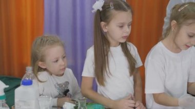 Çocuklar için kimyasal deneyler. Çocuklar kimya dersinden önce koruyucu ekipman giyerler. Oda yapay dumanla dolu..