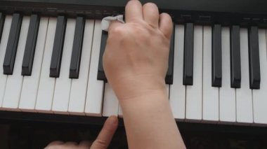 Elektronik piyano. Parmaklar piyano tuşlarına bassın. Bir müzik aletinin klavyesine dikkat et. Beyaz pamuk bir kadının ellerinde..