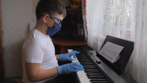 电子钢琴指按钢琴键 手戴橡胶手套 2020年大流行病 自我隔离 身穿防护服 戴口罩 戴手套的男孩 从事音乐工作 孩子们的手放在钢琴键盘上 — 图库视频影像
