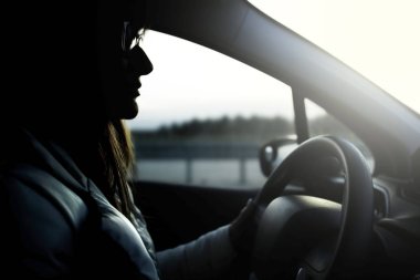 Araba kullanan bir kızın silueti.