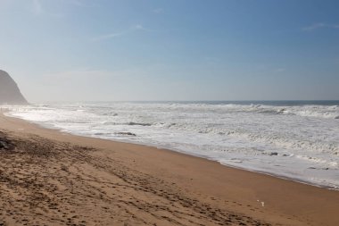 Okyanus kıyısı, köpüklü hareketli dalgalar. Rüzgar gücü. Turkuaz su. 