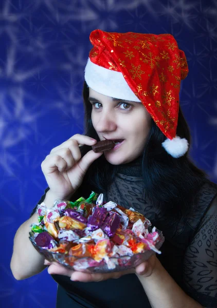 Jonge vrouw in kerstmuts met snoep — Stockfoto