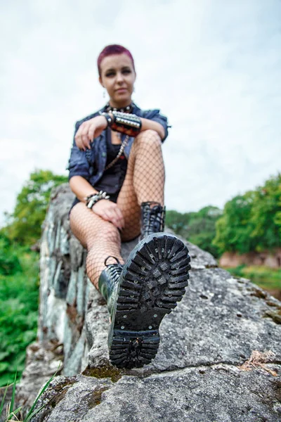 Punk ragazza seduta su un muro di pietra — Foto Stock