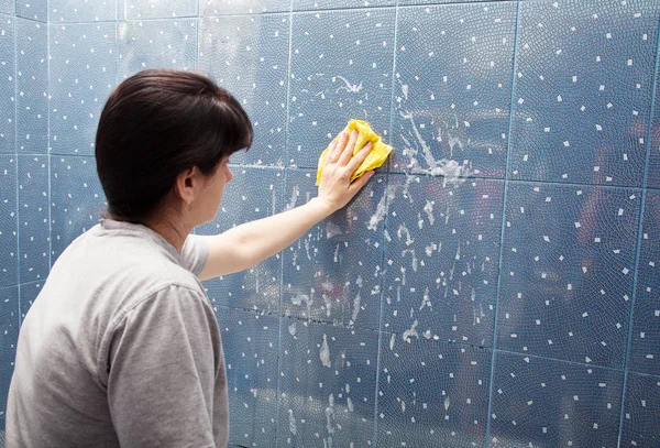 Frau wäscht Fliesen an der Wand mit einem Tuchschaum — Stockfoto