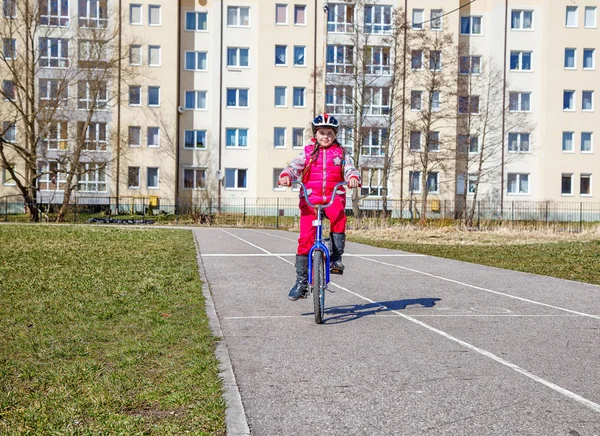 Menina em um capacete de segurança montando uma bicicleta — Fotografia de Stock