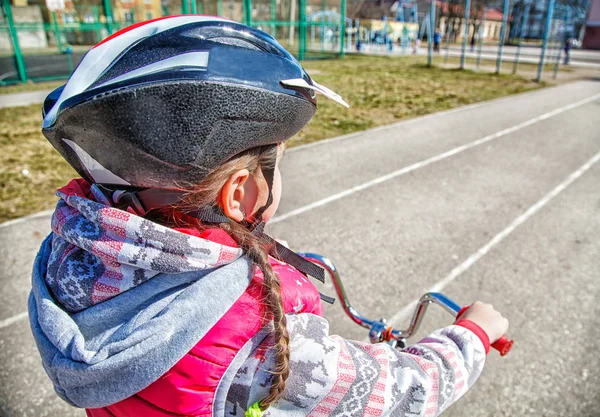 Liten flicka i en skyddshjälm cyklar — Stockfoto