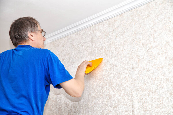 man smoothing the wallpaper with a spatula