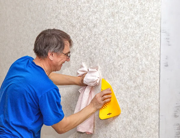 Homme lissant le papier peint avec une spatule — Photo