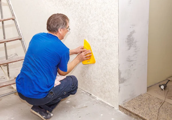 Homme lissant le papier peint avec une spatule — Photo