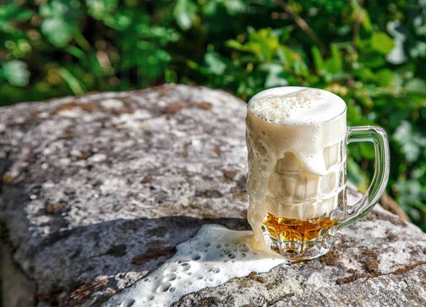 Caneca de vidro com cerveja em pé sobre a pedra grande — Fotografia de Stock