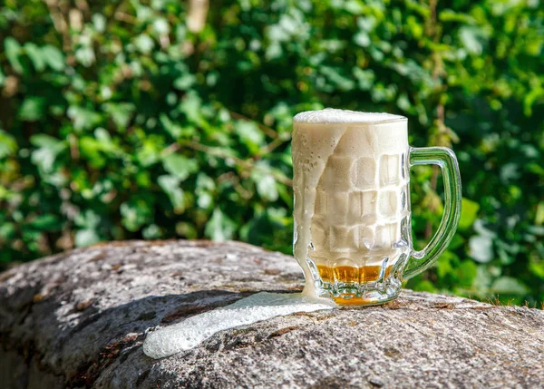 Caneca de vidro com cerveja em pé sobre a pedra grande — Fotografia de Stock