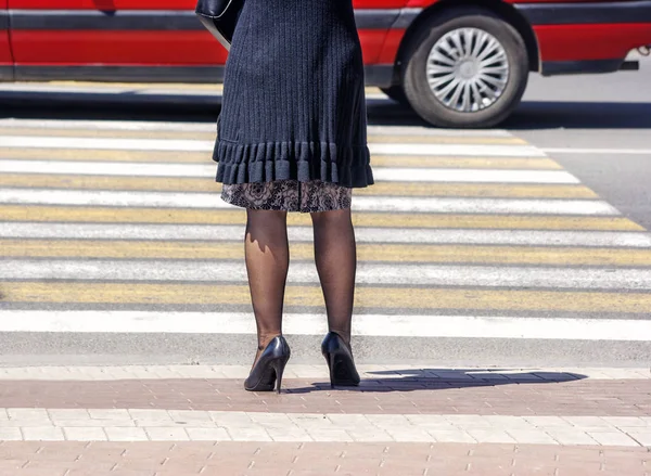 Odottamassa nainen jalankulkijoiden risteyksessä ja autoliikenteessä — kuvapankkivalokuva