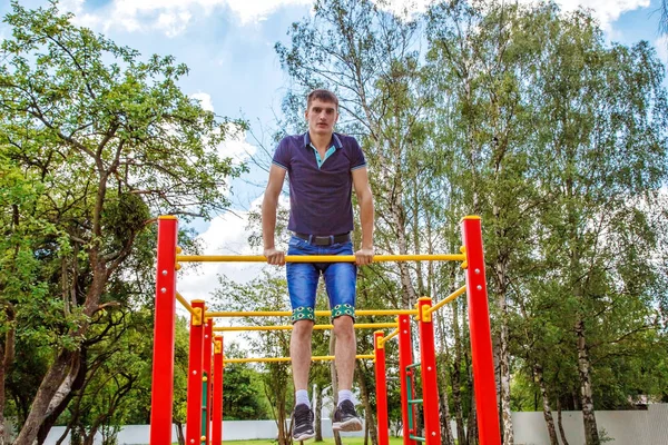 Joven está practicando en una barra horizontal — Foto de Stock