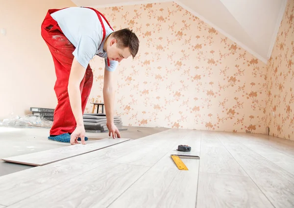 Handyman laying down laminate floor boards — стоковое фото