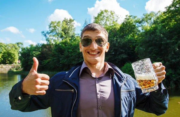 Sonriente hombre sosteniendo una taza de cerveza grande —  Fotos de Stock