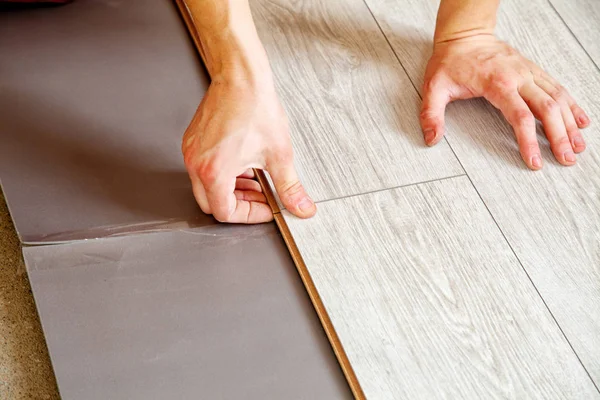 Handyman's hands laying down laminate flooring boards — Stock Photo, Image