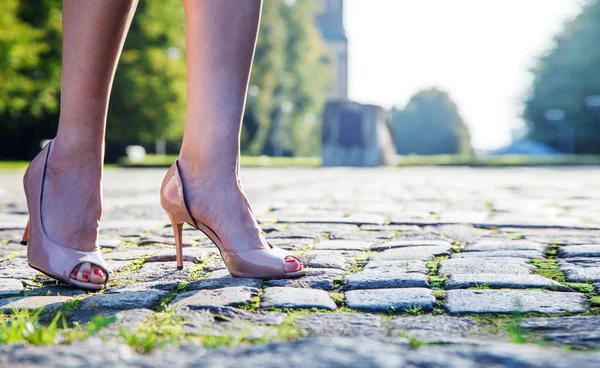 Piernas de una mujer de pie sobre un adoquín — Foto de Stock