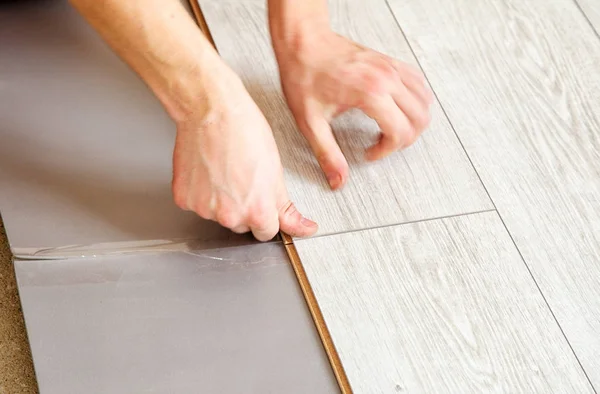 Mani del tuttofare che stabilisce pannelli di pavimenti in laminato — Foto Stock