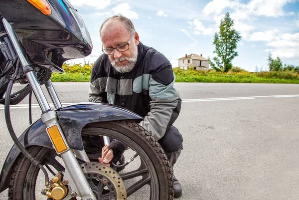 Yaşlı adam motorsikletiyle'nın tekerlek denetler — Stok fotoğraf