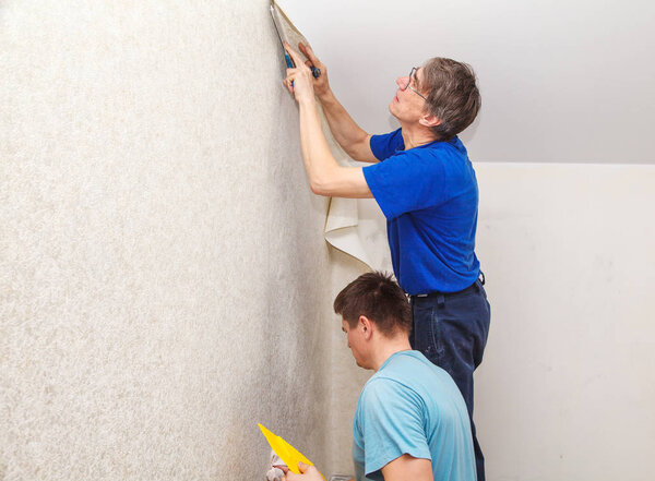 two workers smoothing wallpaper