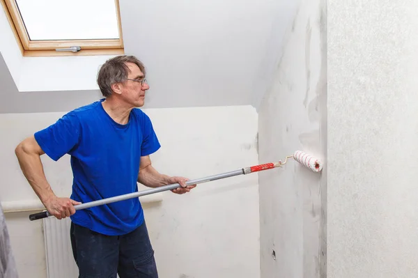 Viejo trabajador pintura pared con pegamento — Foto de Stock