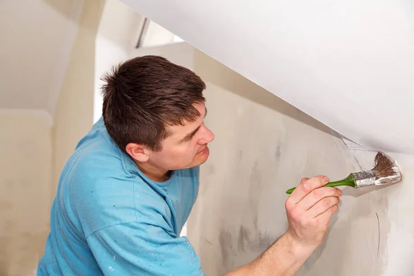 Joven trabajador pintura pared con pegamento — Foto de Stock