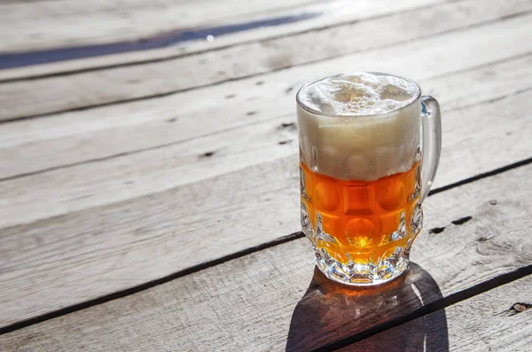 Caneca de vidro com cerveja em pé na mesa ao ar livre — Fotografia de Stock