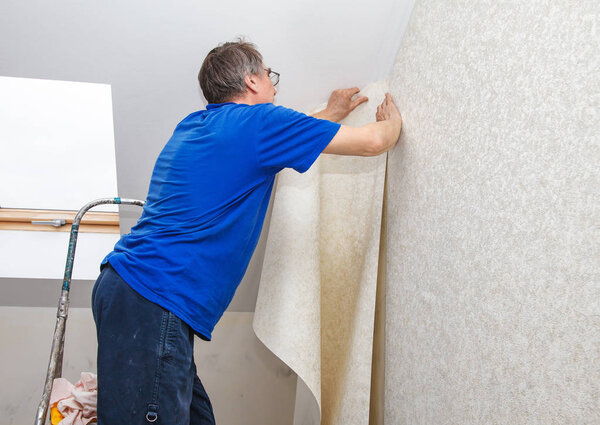 elderly worker smoothing wallpaper