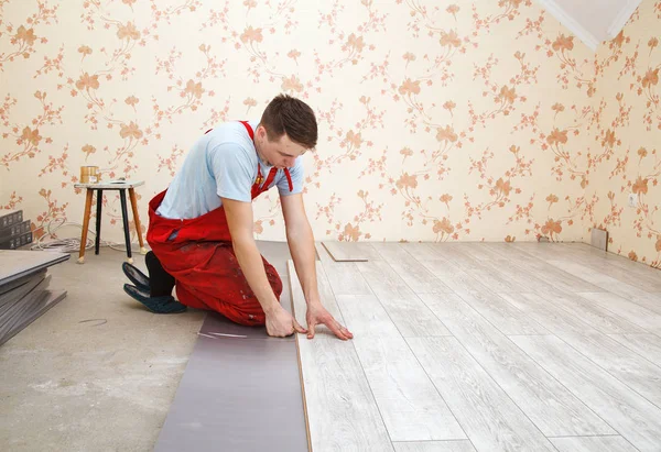 Handyman laying down laminate floor boards — стоковое фото